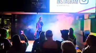 A performer on stage with colorful lights and an audience watching.