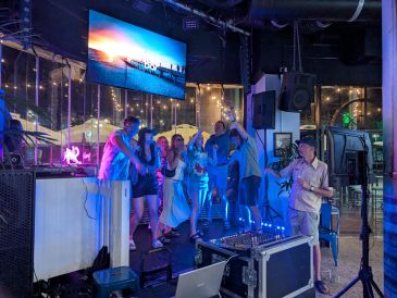 Group of people enjoying karaoke in a lively, neon-lit venue.