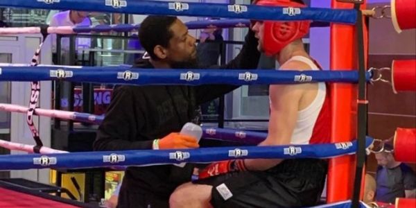 Coach giving advice to a boxer in the ring.