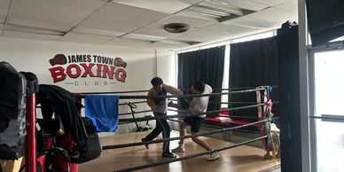 Two men sparring in a boxing ring at James Town Boxing Club.