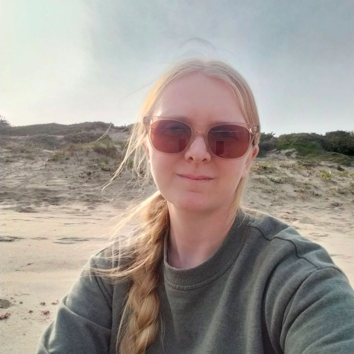 Woman with braided hair and sunglasses on the beach.