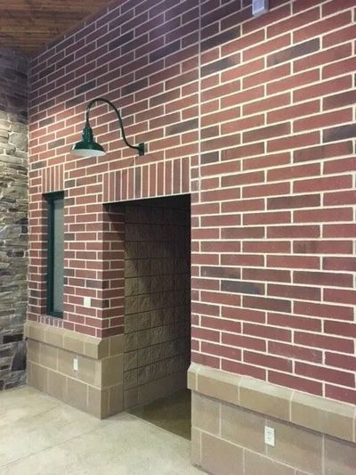 red richbrick wall with doorway and window.  green light above doorway multiple other textured walls