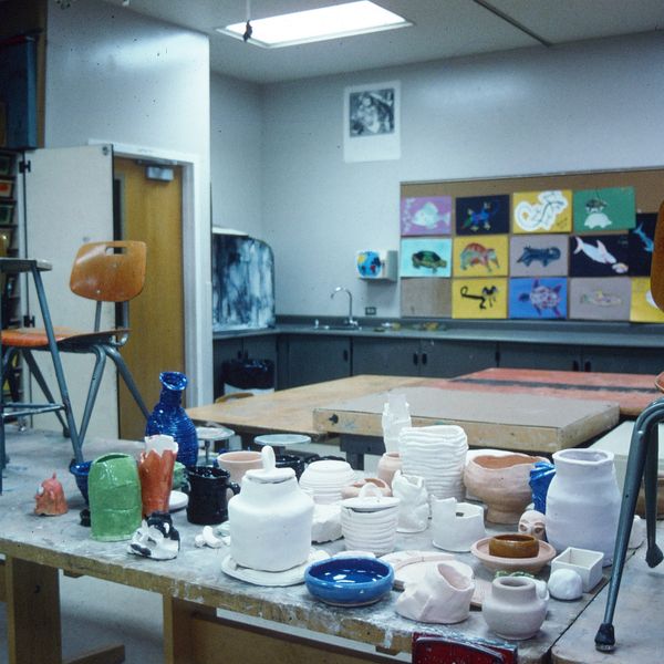Art classroom with pottery projects on a table and colorful animal paintings on the wall.