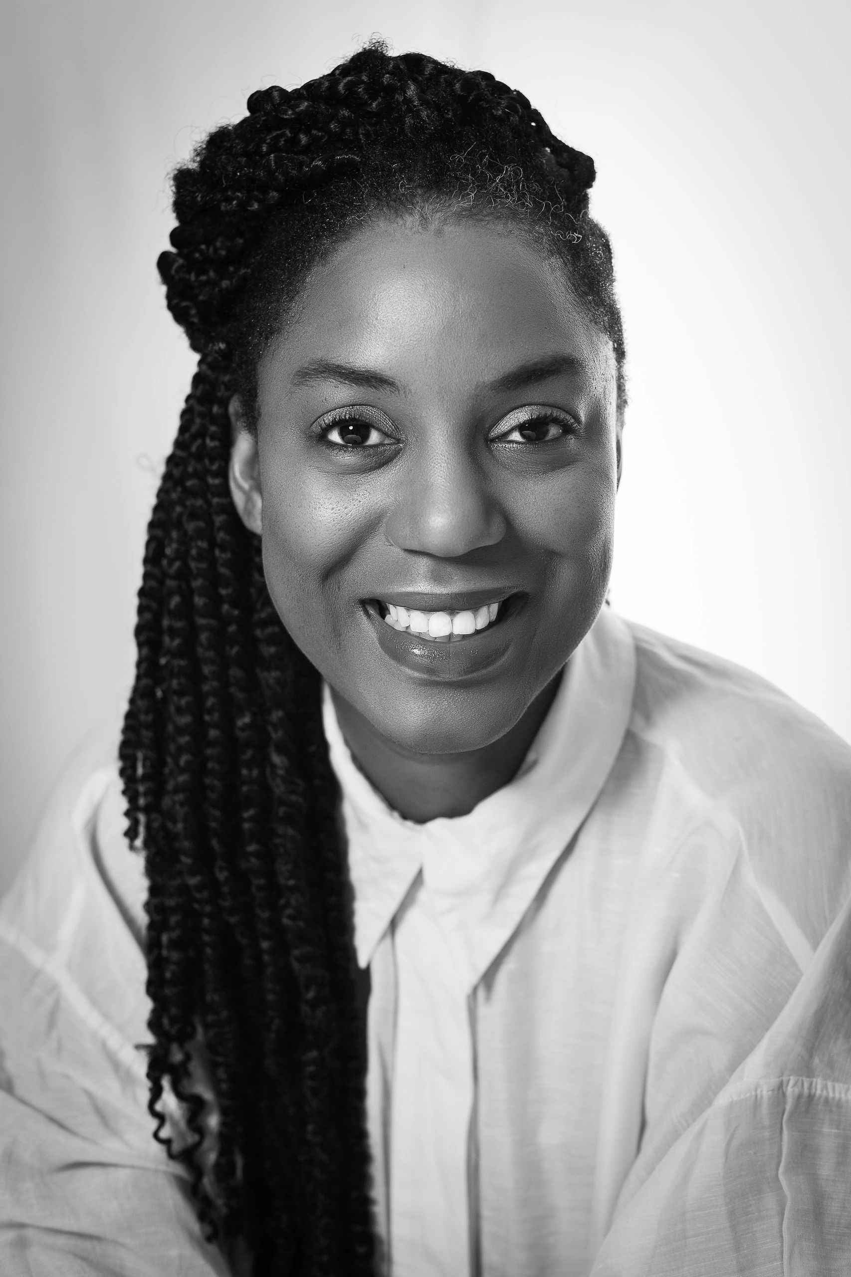 Black and white portrait of a smiling woman with long braided hair.