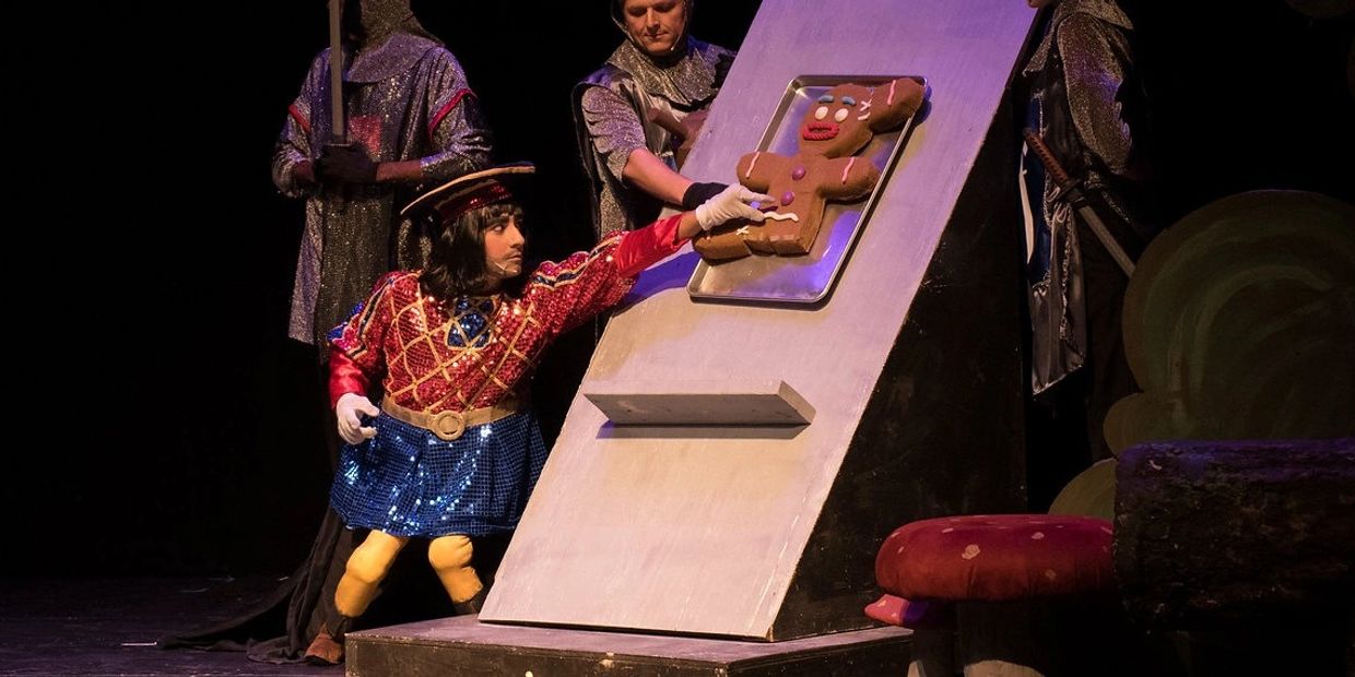 Actor reaching for a gingerbread man on a stage.