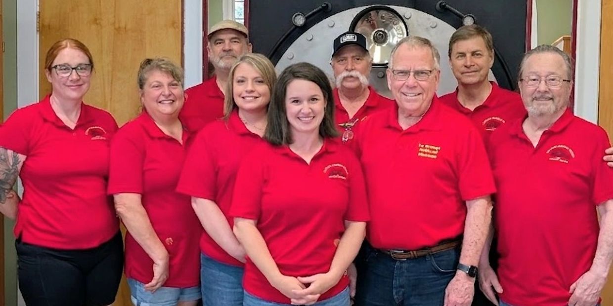 A group wearing matching red polo shirts poses indoors.