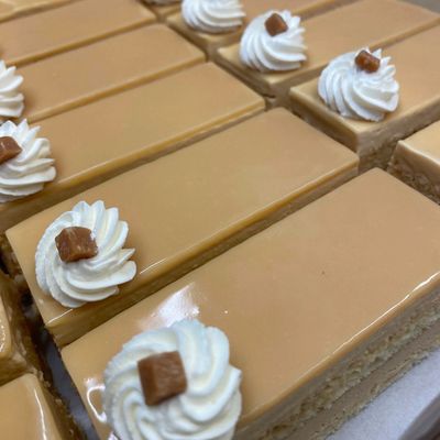 Rows of caramel-glazed cakes with whipped cream and caramel cube toppings.