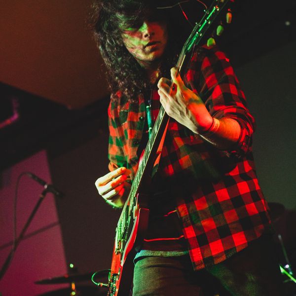Musician passionately playing electric guitar on stage.