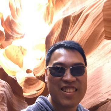 Man wearing sunglasses smiling inside a canyon.