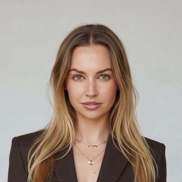 Woman with long blonde hair and brown blazer posing confidently.