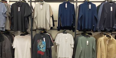 A clothing display in a store featuring sweaters, T-shirts, and jackets under the F&F brand.