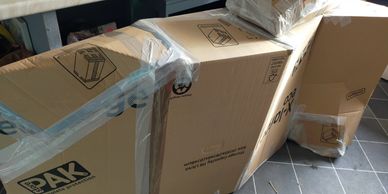 Large cardboard boxes taped together on a tiled floor near a desk.