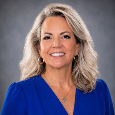 Smiling woman with blonde hair in blue top.