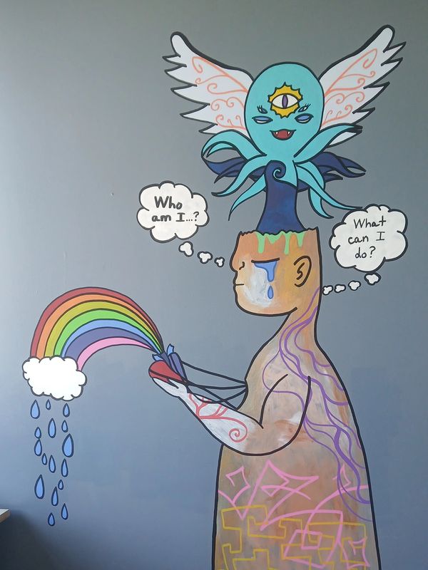 Colorful mural of a figure with a third eye creature and rainbow thoughts.
