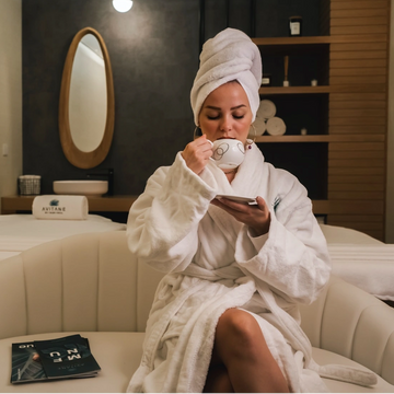 woman drinking coffee wrapped in a robe hair up spa day relaxation