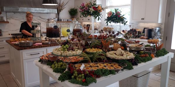 A lavish buffet spread with various appetizers and drinks in a bright kitchen.