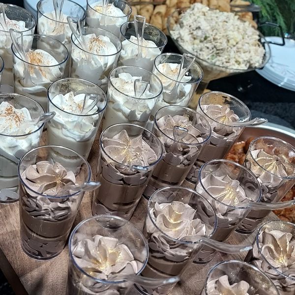 Rows of creamy dessert cups topped with whipped cream and cinnamon.