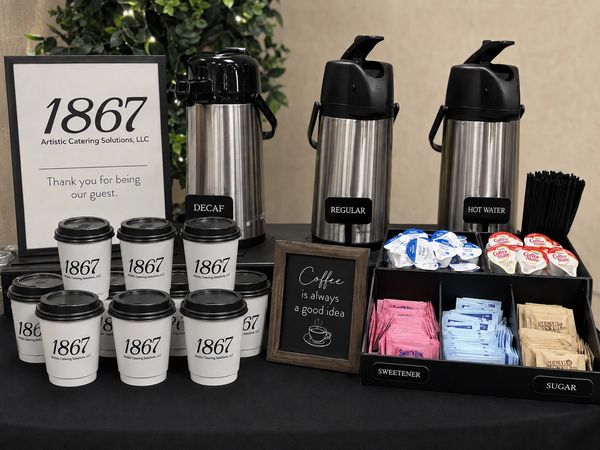 A coffee station with cups, coffee dispensers, and condiments.