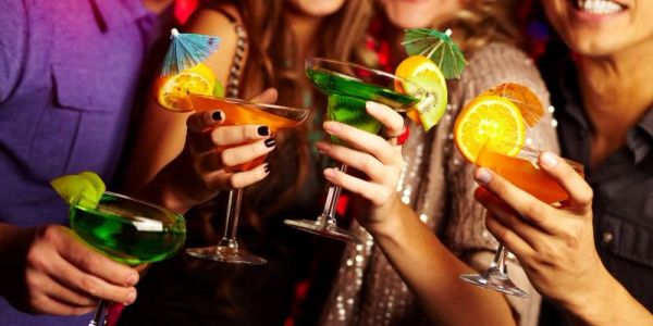 Friends cheers with colorful cocktails at a party.