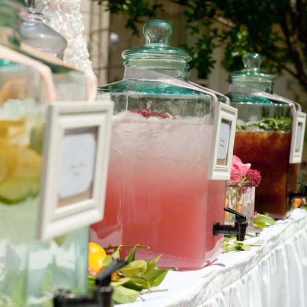 Elegant beverage dispensers with colorful drinks at an outdoor event.