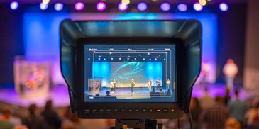 Live event captured through a video camera with colorful stage lighting.