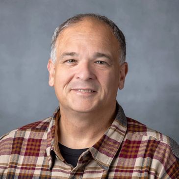 Smiling middle-aged man in a plaid shirt.