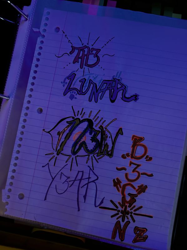 Colorful graffiti-style text and symbols on lined paper in a binder.