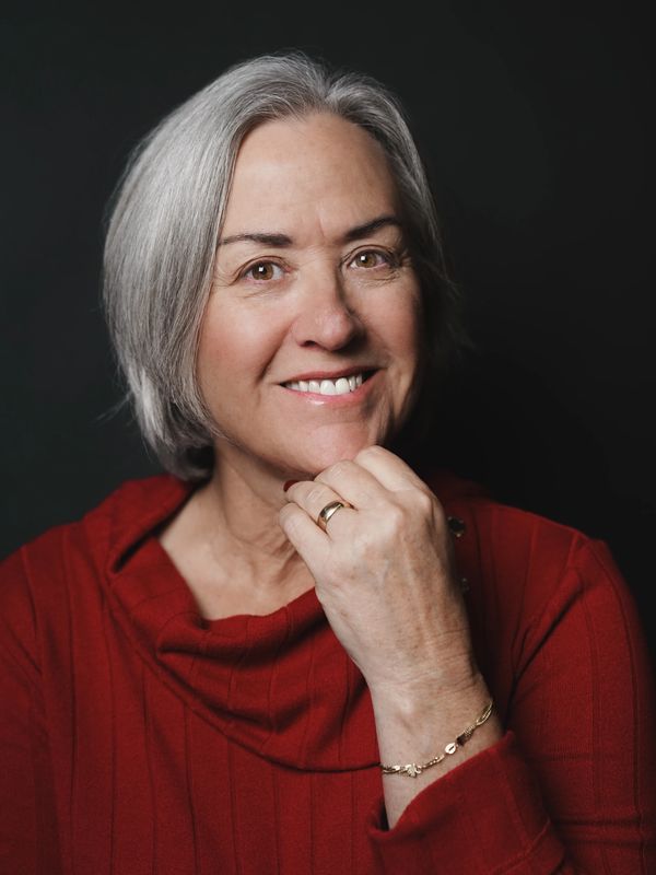 Smiling older woman with short gray hair in a red sweater.