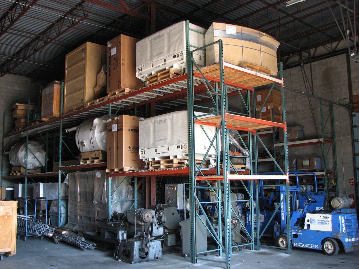 Warehouse storage with pallets, machinery, and a blue forklift.