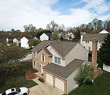Suburban two-story house with attached garage and white car parked outside.