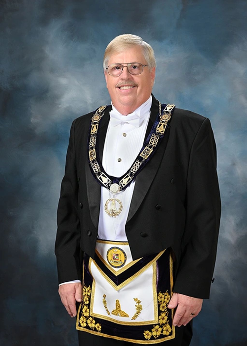 Man dressed in formal Masonic regalia with apron and collar.