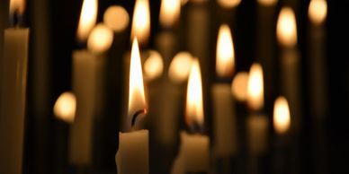 Close-up of lit candles glowing softly in the dark.