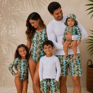 A family of five in matching tropical swimwear poses together.
