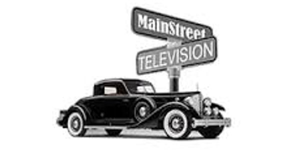 Vintage car parked at Main Street and Television street signs.