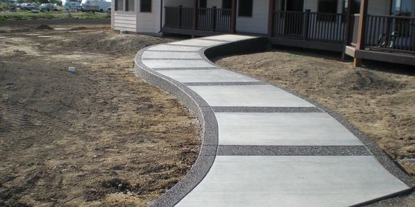 Curved concrete walkway leading to a home’s front entrance.