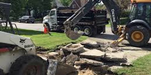 Concrete driveway demolition and removal using construction equipment.