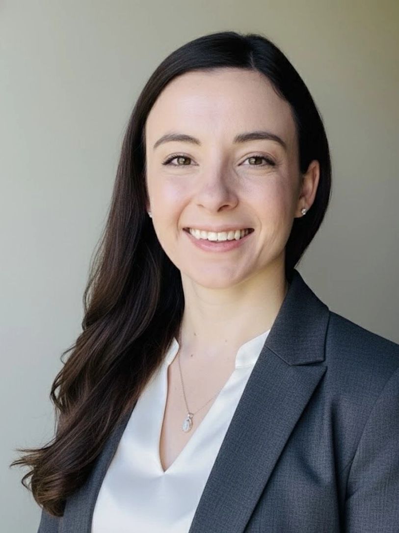 Professional woman in business attire smiling against a neutral background.