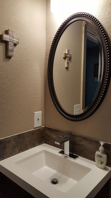 Bathroom sink with wall cross and mirror.