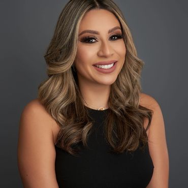 Studio headshot of smiling woman with wavy blonde hair in black sleeveless top