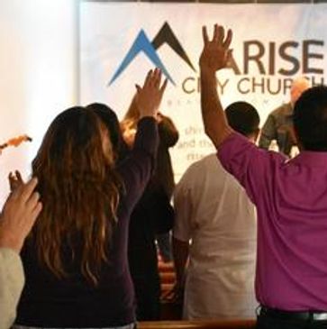 People raising hands in worship at Arise City Church.