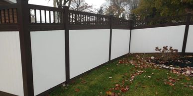 A stylish designer fence featuring a combination of white panels and speckled walnut posts and rails.