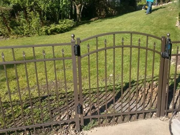 An aluminum gate with vertical pickets and decorative elements on top.