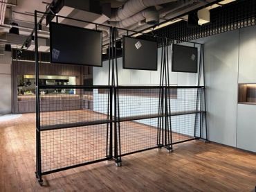 Empty metal grid display stands with mounted screens in a modern indoor space.