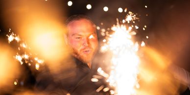 One of the venue staff in a cool picture lighting the sparklers for the couple's sparkler exit.