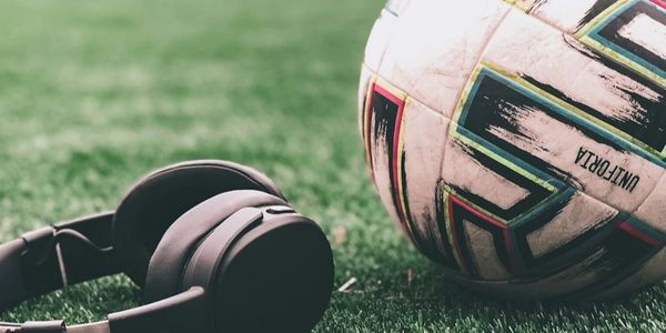 Headphones and a soccer ball on a green field near the white line.