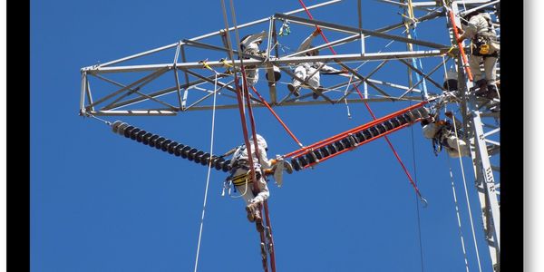 Workers repairing high-voltage power lines on a clear day.