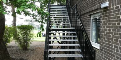 A steel external fire escape staircase powder coated and fitted with galvanised perforated treads.