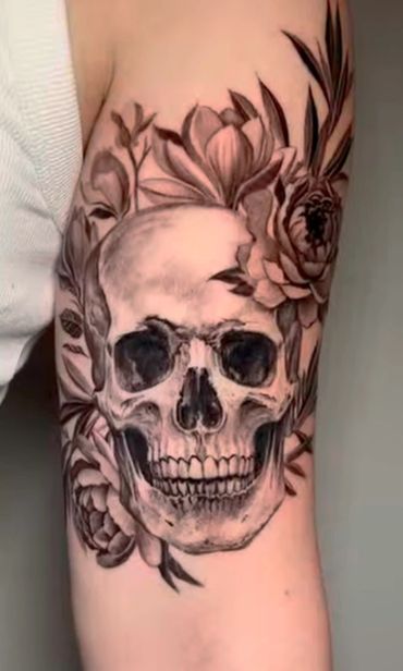 Black and white skull tattoo surrounded by flowers.