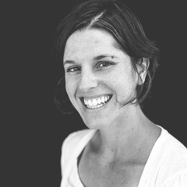 Smiling woman with short hair against a dark background.