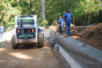 Workers constructing a retaining wall using heavy machinery.